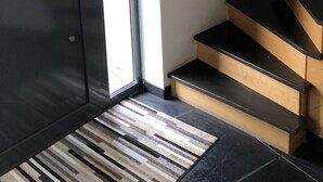 A room with a dark door, a light-colored wall, and a set of wooden stairs with black steps. - Modern country house with spacious rooms and swimming pool (Doingt)
