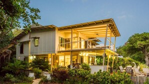A two-story house with a covered patio, a visible staircase, and a garden with various plants. - EEAST on Picnic (Picnic Bay)
