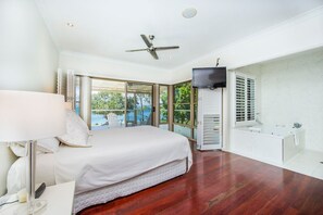Un dormitorio con cama, televisión, ventana y baño.