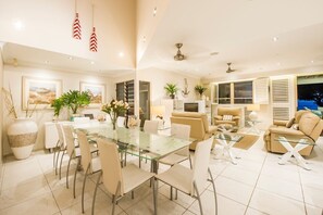 Un salón amplio con una mesa de comedor de vidrio, sofás color beige y un ventanal con contraventanas.