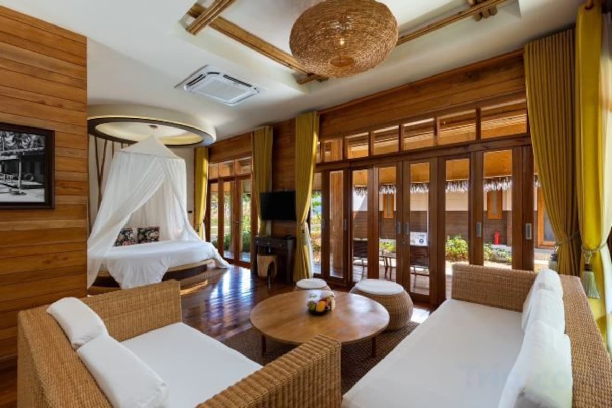 A room with a bed, a sofa, a table, and a television.