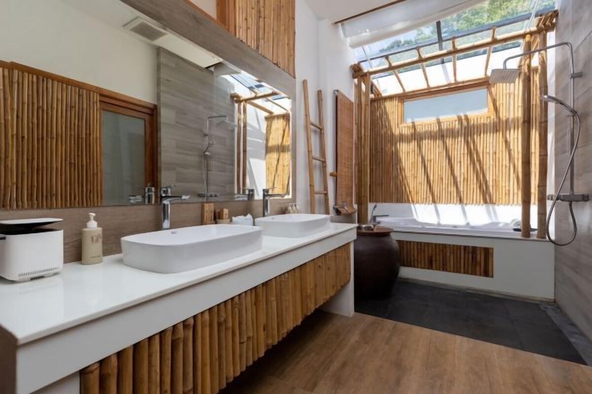 Ein modernes Badezimmer mit zwei Waschbecken, einem großen Spiegel und einer Duschkabine.