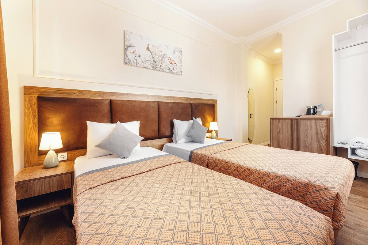 A hotel room with two beds, wooden headboards, and a painting on the wall.