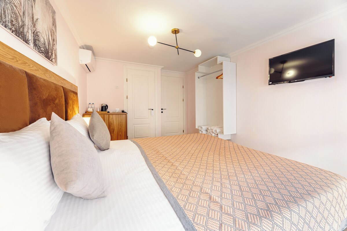 A bedroom with a bed, a TV mounted on the wall, and a wardrobe.
