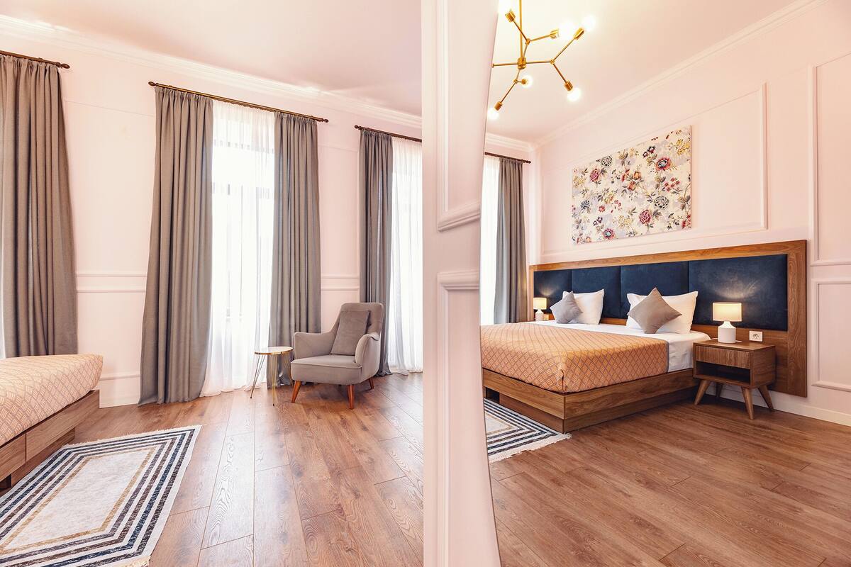 A hotel room with a bed, a chair, a small table, and a nightstand.