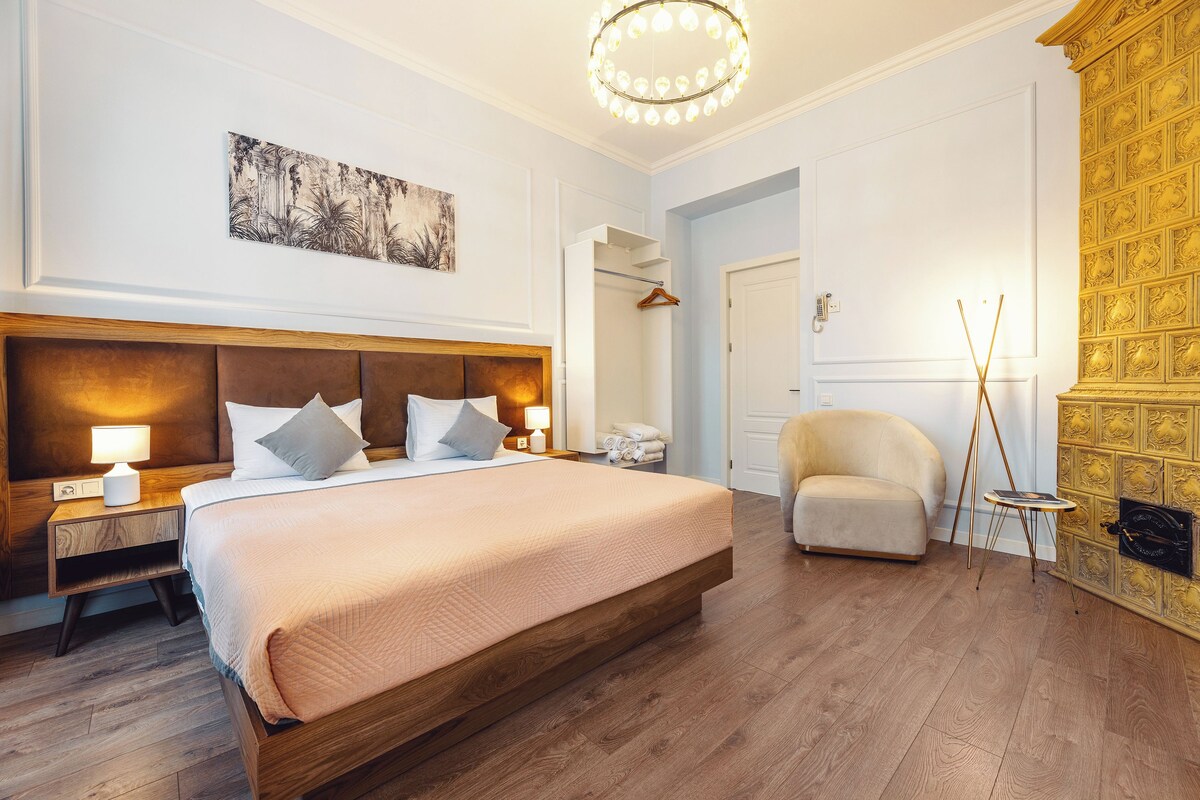 A bedroom with a large bed, bedside tables, a wardrobe, a chair, and a decorative wall.