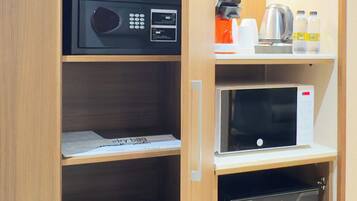 Habitación de hotel con microondas, cafetera y refrigerador pequeño.