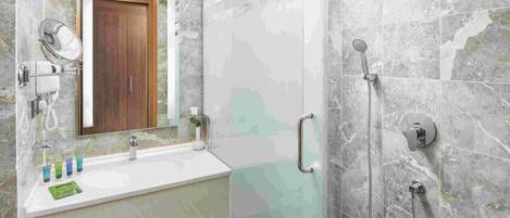 A bathroom with a sink, mirror, and shower.