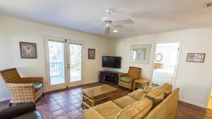 A living room with a large sofa, a television, wicker chairs, and a ceiling fan. -  Lake front, with Gulf View! Perfect for large groups! 10 min walk to beach. (Blue Mountain Beach)