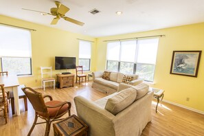 Una sala de estar con sofá, sillones, televisor y comedor.