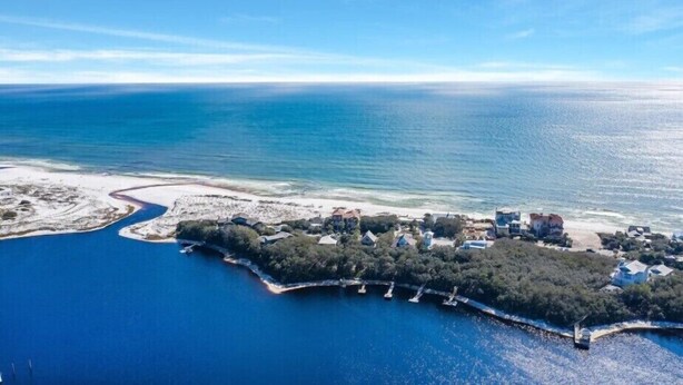 Luftaufnahme eines Küstengrundstücks mit einer Marina, Strand und Wohnhäusern.