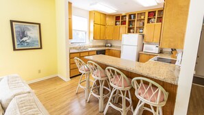 A kitchen with wooden cabinets, a granite countertop, and bar stools. -  Lake front, with Gulf View! 10 min walk to beach. (Santa Rosa Beach)