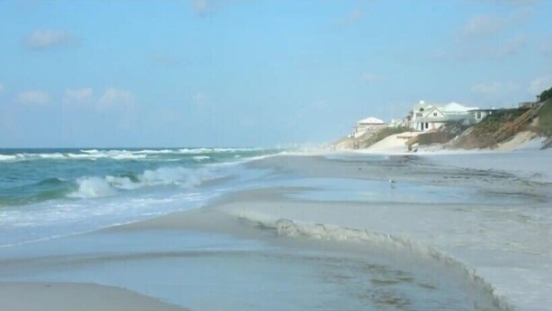 A beach with waves, a sandy shore, and buildings in the background. -  Lake front, with Gulf View! 10 min walk to beach. (Santa Rosa Beach)
