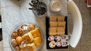 Een tafel met potten vol noten en gedroogd fruit, een schaal gebak en een dienblad met brood en Nutella.