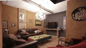 A cozy living room with leather sofas, a wooden coffee table, a TV, and a chandelier.