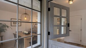 Un comedor con una mesa y sillas de madera, una lámpara colgante y una puerta blanca al fondo.