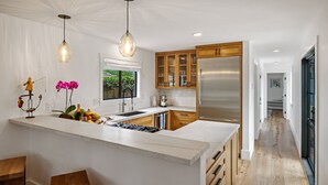 Una cocina moderna con una isla grande, armarios de madera y electrodomésticos de acero inoxidable.