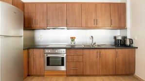 Une cuisine avec des meubles en bois, un réfrigérateur en acier inoxydable, une cuisinière et une machine à café.
