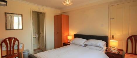 A bedroom with a bed, bedside tables, a mirror, a wardrobe, and a chandelier.
