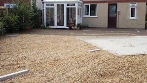 A residential property with a conservatory, a gravel driveway, and a garden area. - Mount Lavinia (Sheringham)