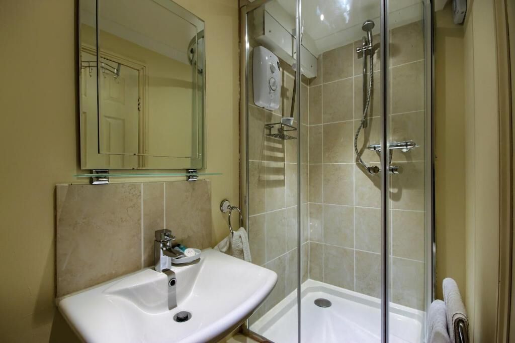 A bathroom with a glass-enclosed shower, a sink, and a mirror.
