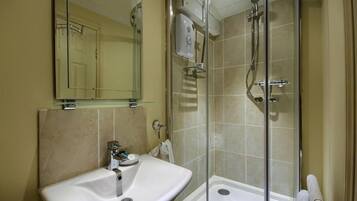 A bathroom with a glass-enclosed shower, a sink, and a mirror.