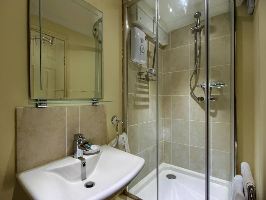 A bathroom with a glass-enclosed shower, a sink, and a mirror.