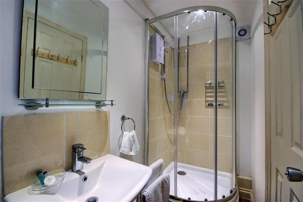 A bathroom with a glass-enclosed shower, a sink with a mirror above it, and a towel rack.