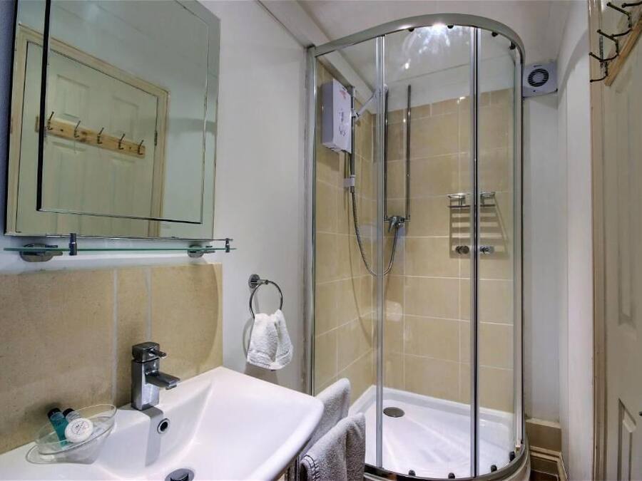 A bathroom with a glass-enclosed shower, a sink with a mirror above it, and a towel rack.