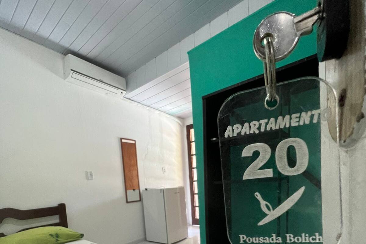 Une chambre à coucher avec un lit, un mur vert et une porte sur laquelle est apposée une plaque indiquant « Appartement 20 ».