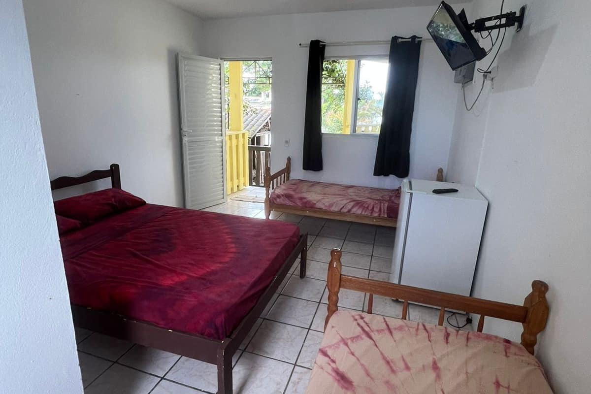 Une chambre avec deux lits simples, un bureau, une chaise et un téléviseur fixé au mur.