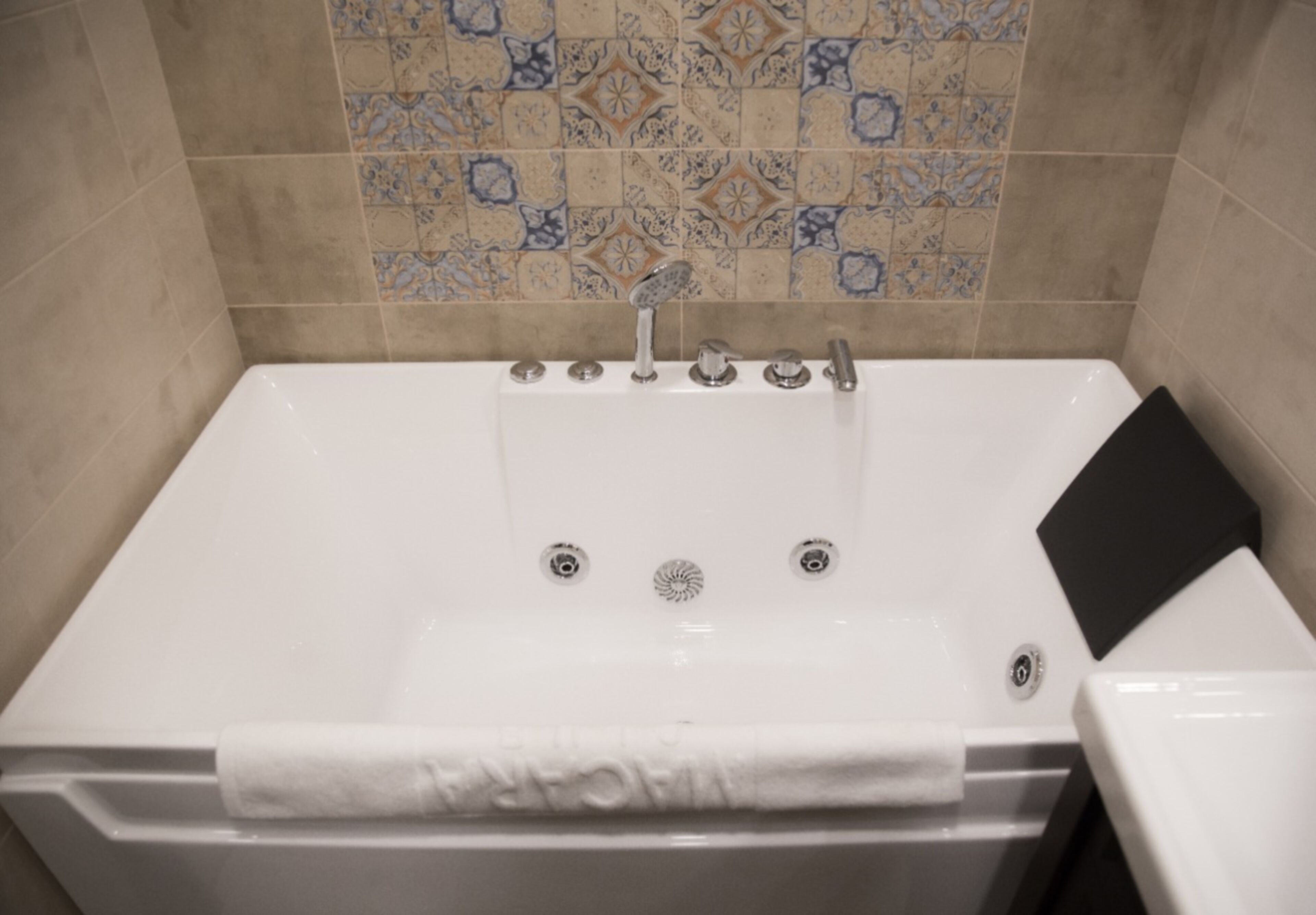 A white bathtub with multiple faucets and a black mat.