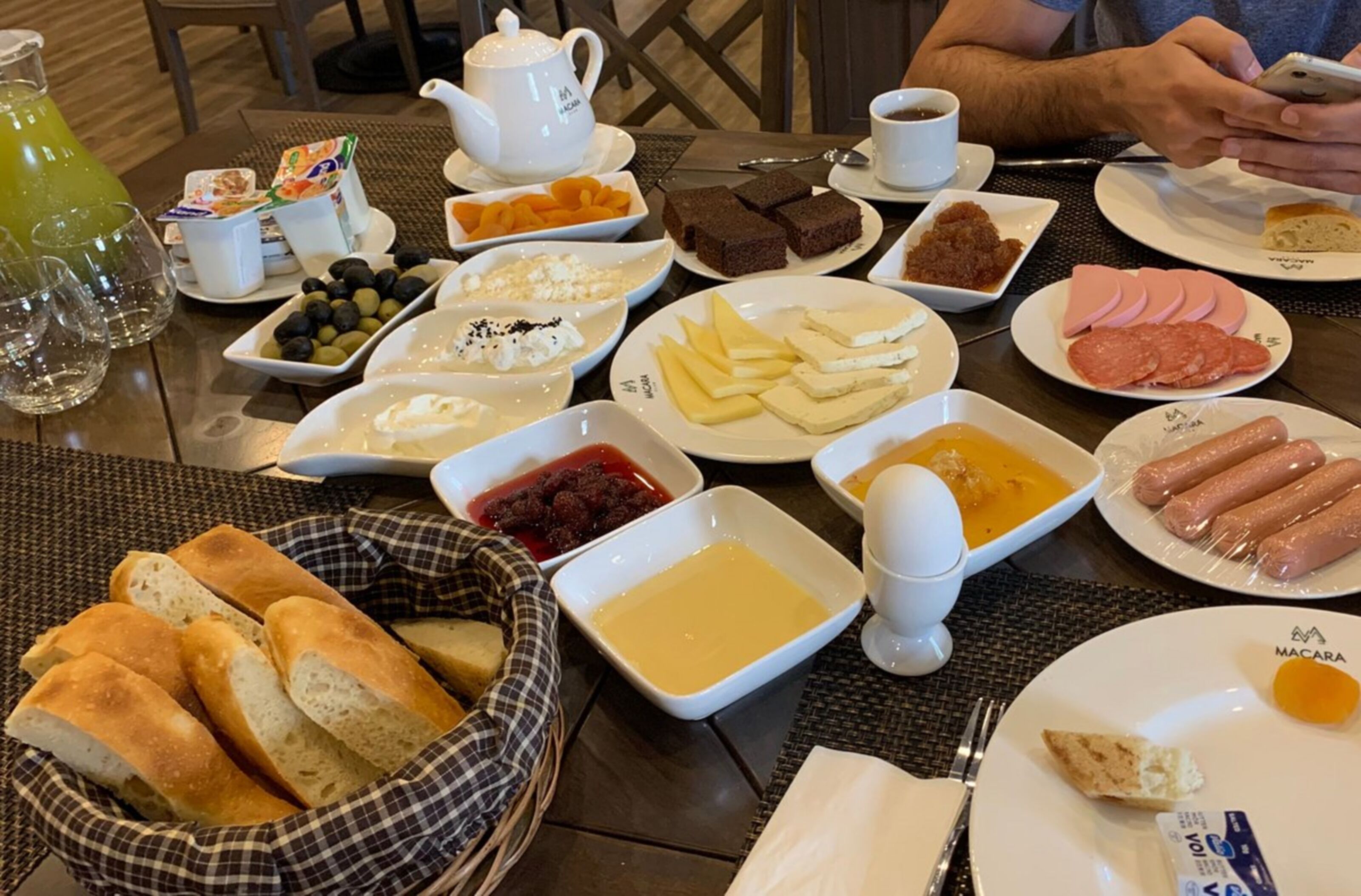 A breakfast table with various food items, including bread, cheese, and meats.