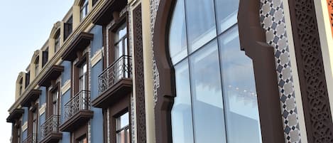 A multi-story building with a large arched window and decorative tile patterns.