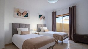 Habitación de hotel con dos camas, una mesita de noche, una lámpara y obras de arte en las paredes.