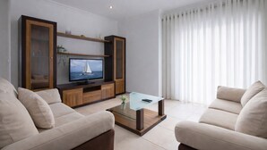 Una sala de estar moderna con televisor, sofá y mesa de centro.