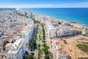Vista aerea di una città costiera con grattacieli, una strada principale e una spiaggia.