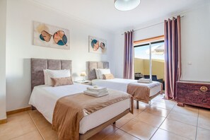 A hotel room with two beds, a dresser, and artwork on the walls. - Apartament Alameda | 2 Bedrooms | Spacious Balcony | Quarteira (Quarteira)