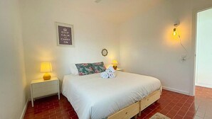 Un dormitorio con una cama, dos mesitas de noche con lámparas, un reloj de pared y un cartel que dice "KEEP CALM AND CARRY ON".