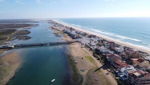 Vista aérea de una zona costera con playa, un muelle y edificios residenciales.