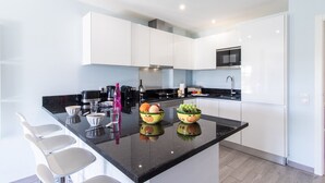 Una cocina moderna con armarios blancos, encimera negra y una isla central con asientos.