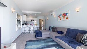 Una sala moderna con un sofá, una mesa de centro y una zona de bar con taburetes.