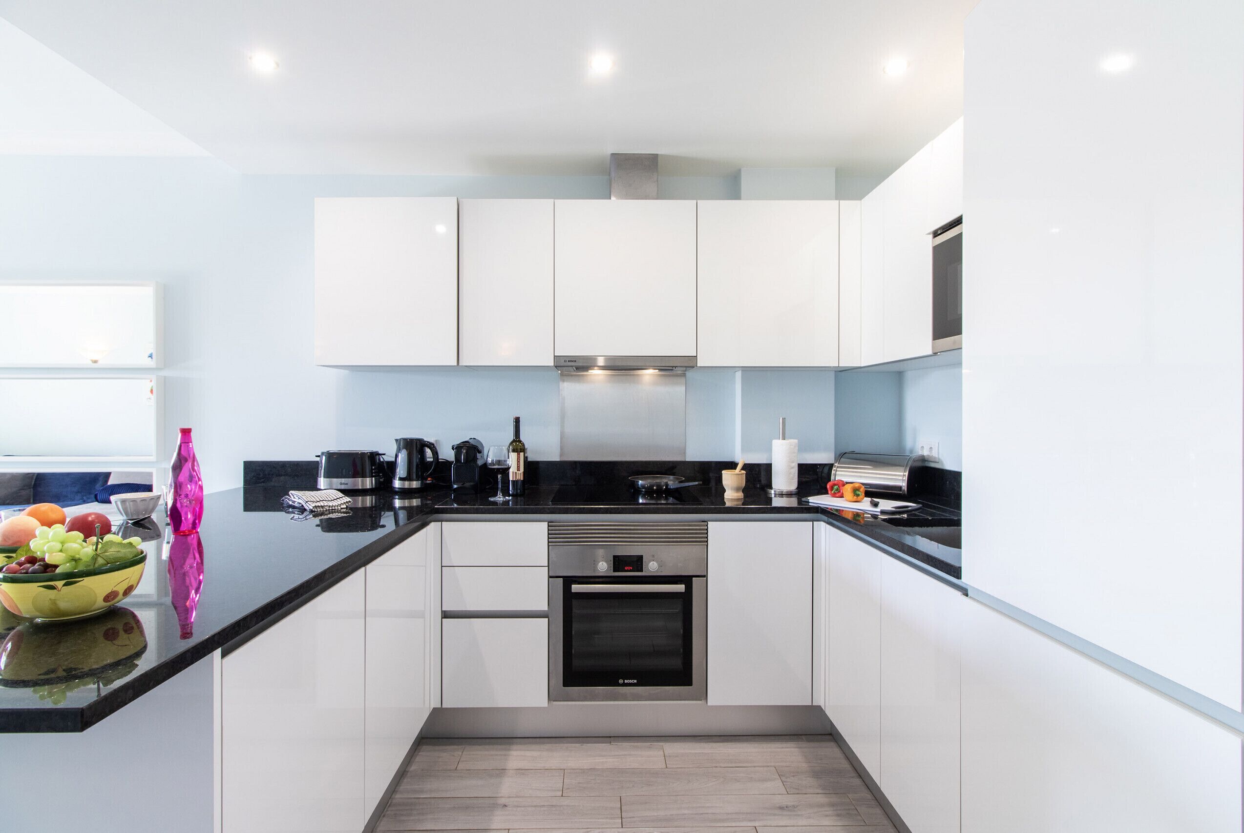 A modern kitchen with white cabinets, a black countertop, and stainless steel appliances.