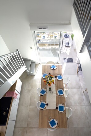 Un coin repas avec une table en bois, six chaises et un vase de fleurs.