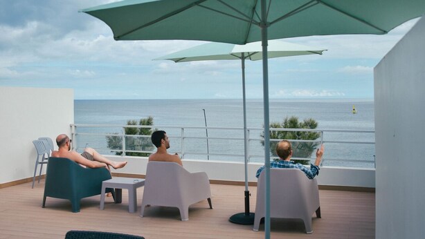 A balcony with three chairs and a table, overlooking the sea. - Hostel AzorAzul (Ponta Delgada)