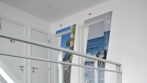 A modern interior with a glass railing staircase leading to a second floor. - Hostel AzorAzul (Ponta Delgada)