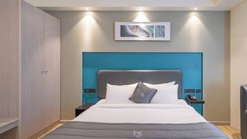 A hotel room with a bed, a wardrobe, a nightstand, a phone, and a painting on the wall.