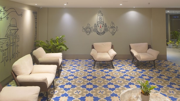 A lobby with a patterned floor, a chandelier, and seating areas. - Republic Inn (Tirupati)