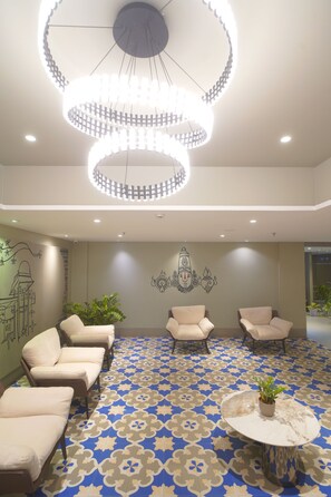 A lobby with a patterned floor, a chandelier, and seating areas.