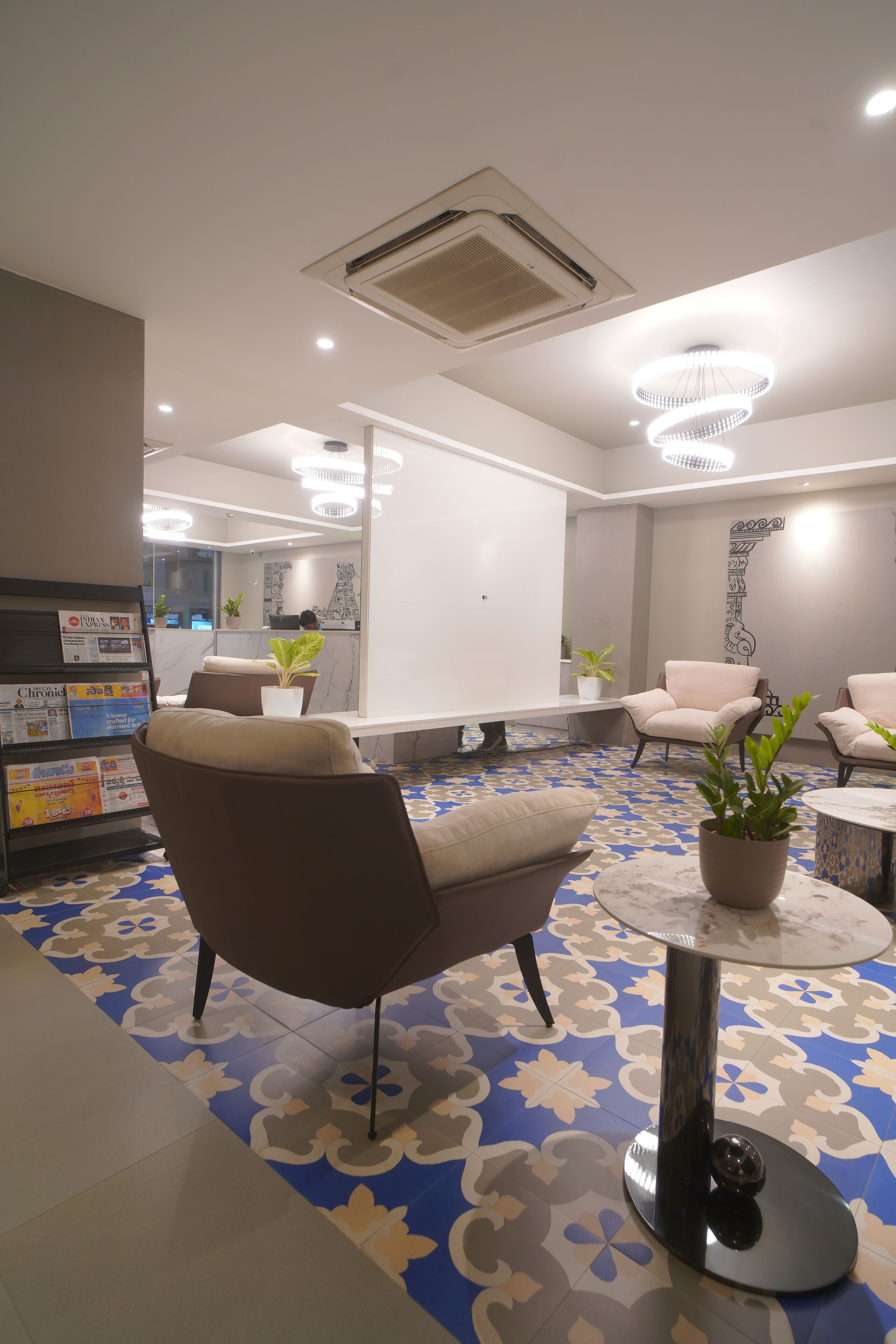 En moderne lobby med et mønstret gulv, siddeområde og en receptionsdisk.